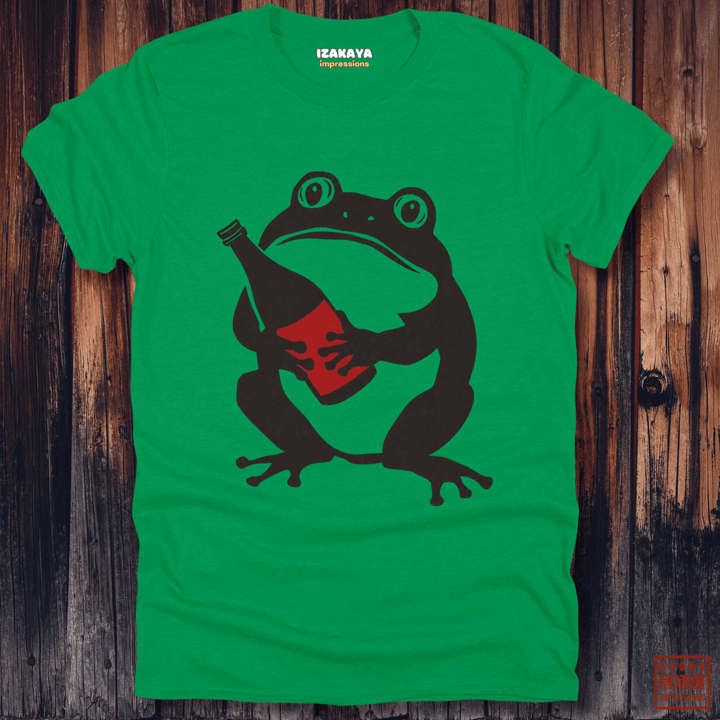 A bright green crewneck t-shirt featuring a graphic of a dark brown frog holding a red bottle, laid flat on a rustic dark wood plank background. The brand name 'IZAMAYA' is printed inside the collar.